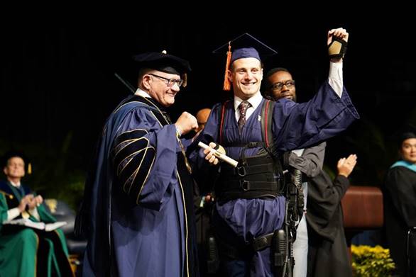 Aldo Amenta '18 crosses the commencement stage with the help of an exoskeleton